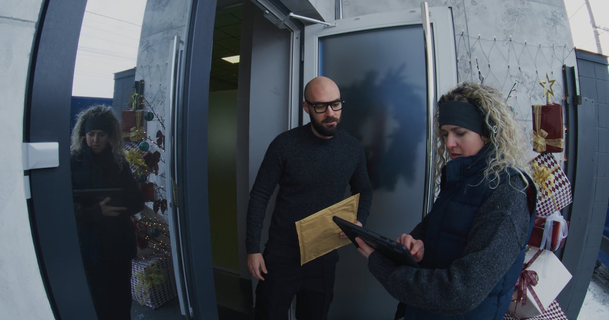 Courier handing a large document envelope to a recipient at a front door